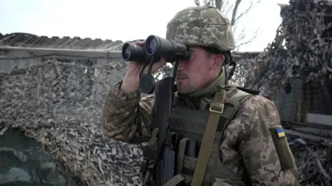 Getty Images A Ukrainian serviceman patrols at the checkpoint in the village of Shyrokyne near Mariupol, in eastern Ukraine, April 2021