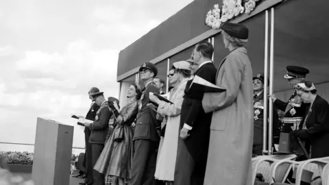 PA Media The Queen laughs as she watches a fly past with the Duke of Edinburgh at Odiham Airfield in 1953. She is also joined by the Duke and Duchess of Gloucester, the Duchess of Kent and Princess Alexandra, aged 16.