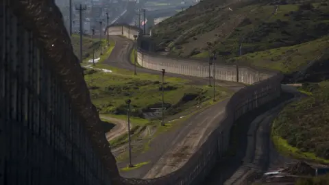 Getty Images The existing barricade - made of steel wall, fences, and razor wire - is seen winding along the US-Mexico border in San Ysidro, California.