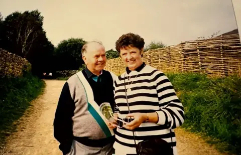 Hawkes family A photo of the late Olive Hawkes. She has short, curly brown hair and is wearing a black and white striped jumper.
