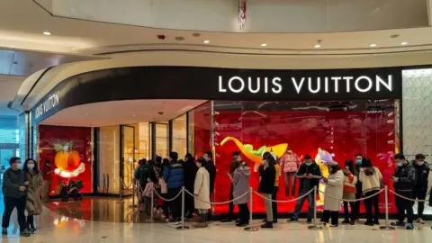 Getty Images Chinese shoppers queue in front of luxury store