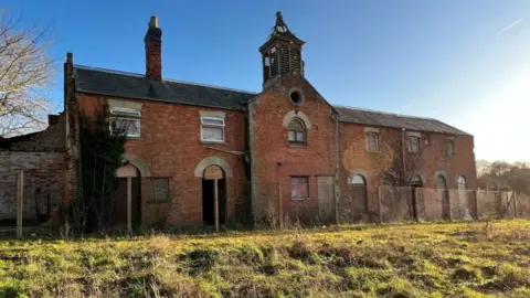 Talbot Homes Two-storey red brick building with with small pointed tower