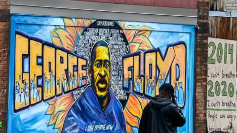 AFP A man walks past the mural of George Floyd