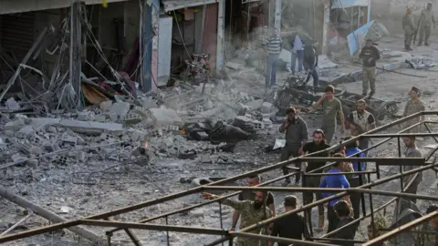 AFP Turkey-backed Syrian fighters inspect the site of a car bomb explosion in the northern Syrian Kurdish town of Tal Abyad, on the border with Turkey, on November 2, 2019.