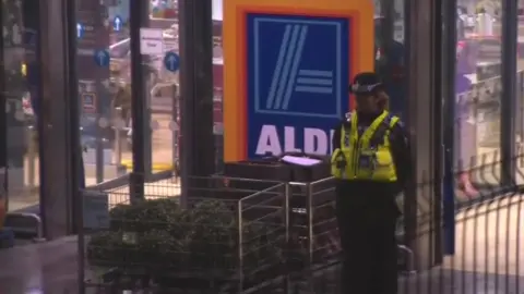BBC A policewoman outside the Aldi