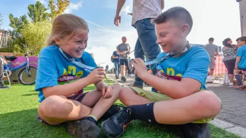 NNP A girl and a boy smile as they compare their medals