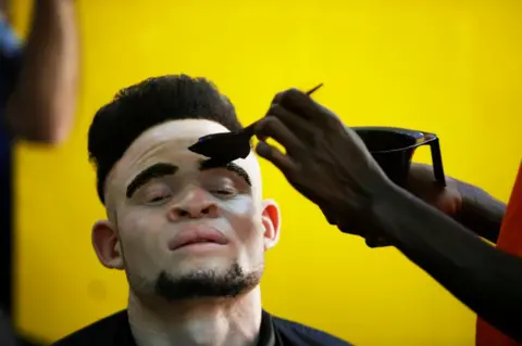 Reuters A make up artist works on a participant