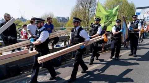 AFP Officers carry away pieces of wood as they break up the climate change activist's camp on Waterloo Bridge