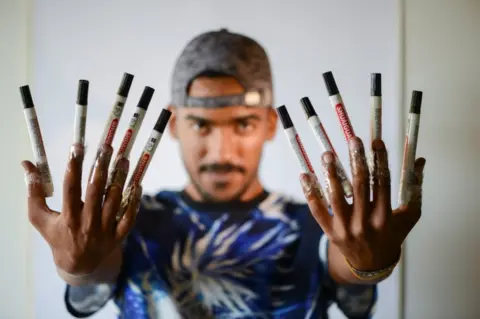 Reuters Artist Mohammed Mahmoud (Amedo), 27, tapes markers on his hands at studio in Benghazi.