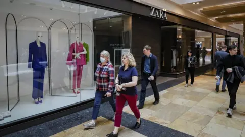 EPA People walk in front of a closed Zara shop at a shopping centre in Moscow, Russia, 26 May 2022