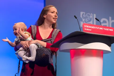 Dan Kitwood / Getty Images Catherine Atkinson, the Labour parliamentary candidate for Erewash, holds her nine-month-old daughter as she addresses delegates at the Labour Party conference in Brighton