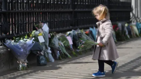 EPA A young girl holds flowers outside Buckingham Palace on 9 April 2021