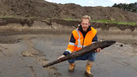 Provincie Zuid-Holland Dutch archaeologist Jeroen Loopik with a Roman oak pile, Katwijk, 2018