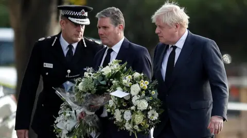 Reuters Chief Constable of Essex Police B. J. Harrington, Britain"s Labour Party leader Keir Starmer and Prime Minister Boris Johnson arrive to pay tribute at the scene where British MP David Amess was stabbed to death