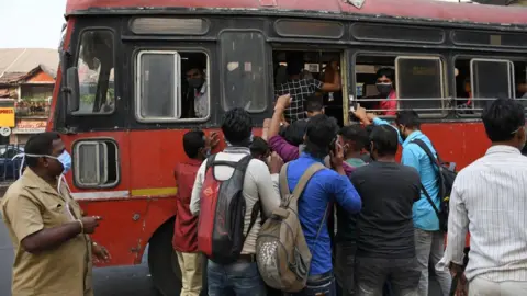 Getty Images A crowd of people boarding a public transport bus in Mumbai. Covid-19 cases are spiralling in Maharashtra state as people are not maintaining social distance while travelling to work.