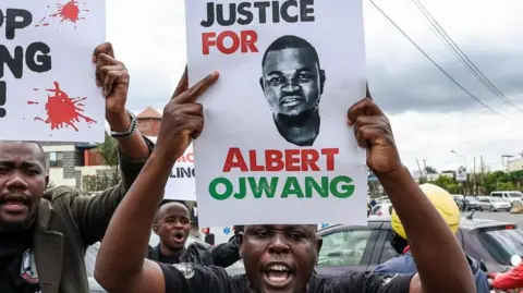 A protester holds a placard with Albert Ojwang's picture written 'Justice for Albert Ojwang'.