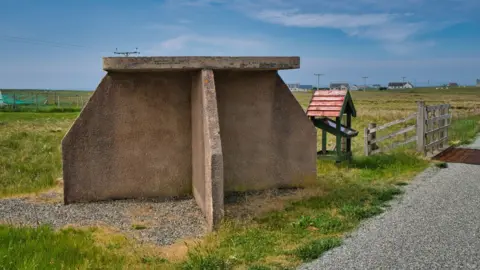 Getty Images The bus shelter in a rural landscape is made from concrete slabs and designed in a way to offer protection against wind and rain coming from the sides and above.