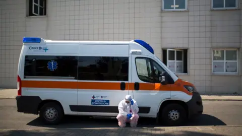 Getty Images A health worker dressed in a protective suit outside a hospital in Rome