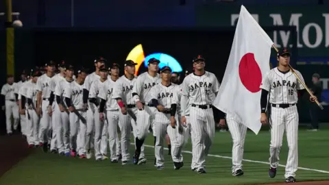 Getty Images Shohei Ohtani leads his teammates onto the field while carrying the Japanese flag prior to the game against the United States.