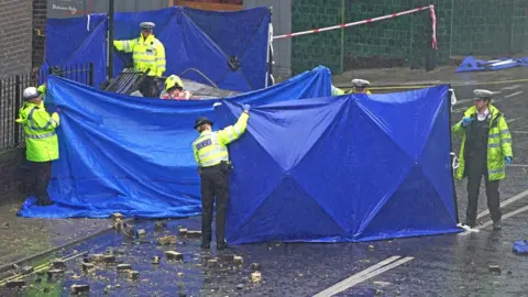 PA Media Police officers erect tarpaulin