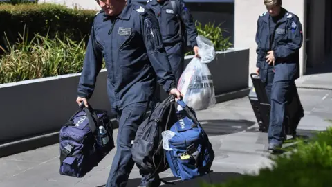 Police officers remove bags from the Italian consulate in Melbourne
