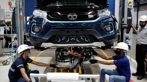 Reuters Workers install the electric motor inside a Tata Nexon electric sport utility vehicle (SUV) at the Tata Motors plant in Pune, India.