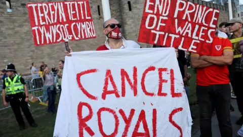 Reuters A man holds signs and a banner during a protest outside Cardiff Castle on 16 September, the King's first visit to Wales since the death of the Queen