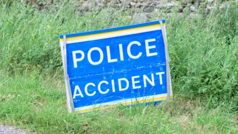 Richard Johnson via Getty Images Police accident sign on a grass verge