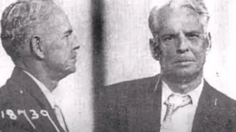 FBI Archives An FBI mugshot from the day of his arrest on 23rd November 1965. He has white wispy hair, and his tie and shirt look dishevelled