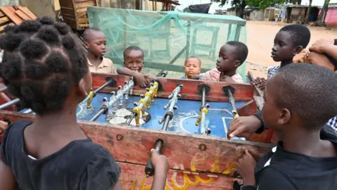 AFP Children standing around a football table playing.
