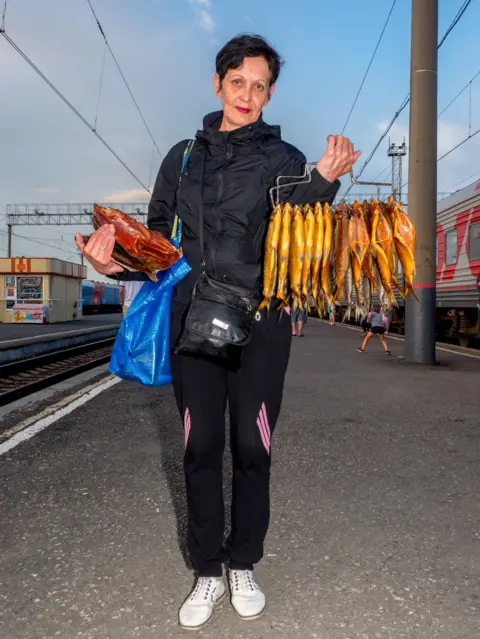 Peter Dench A woman sells smoked fish on the platform at Barabinsk in Russia