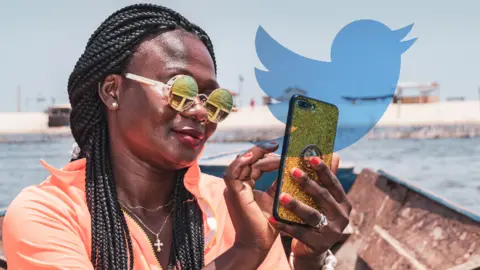 Getty Images A woman in Ghana using a phone with the Twitter logo in the background