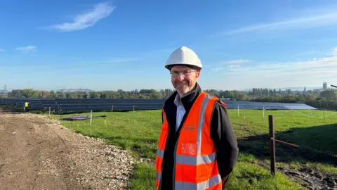 Graeme Buckman stood in front of solar panels at the old Hempstead landfill site.