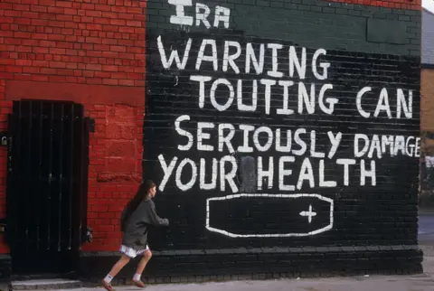 Getty Images 1980s pic of wall with graffiti: "IRA warning touting can seriously damage your health"