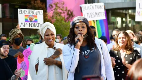 Getty Images Blossom C. Brown speaks and Stand Up in Solidarity rally organizer Ashlee Marie Preston looks on as Trans employees and allies at Netflix walkout in protest of Dave Chappelle special on October 20, 2021 in Los Angeles, California