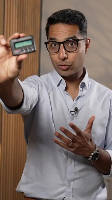 A man holding a pager towards the camera.
