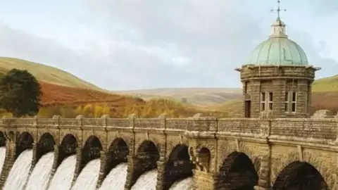 Severn Trent The Elan Valley Aqueduct, which consists of many stone arches which allow water to flow through, and a lead-roofed control building, against a backdrop of the Welsh hills