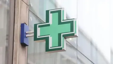 PA Media Green cross sign outside pharmacy window
