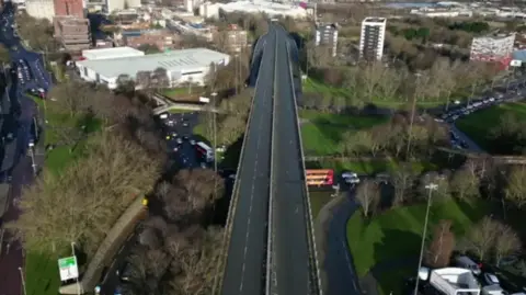 Aerial view of the empty Gateshead flyover road, with high rise buildings in the distance