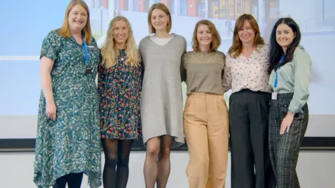 Sofiia Rozhdestvina Sofiia Rozhdestvina is pictured with five other women standing in a row smiling at the camera. She is wearing dark patterned trousers and a light green top and has long dark hair.