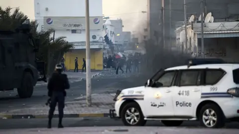 AFP Bahraini protesters throw stones towards riot police during clashes in the village of Shahrakkan, south of Manama, on 5 April 2016