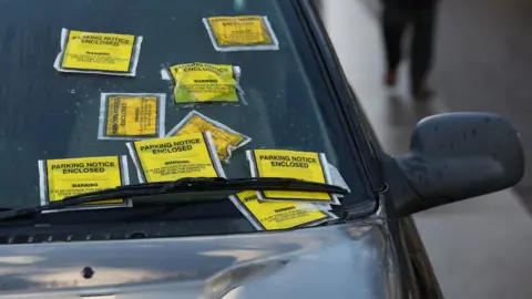 Parking notice fixed penalties attached to the windscreen of a Land Rover