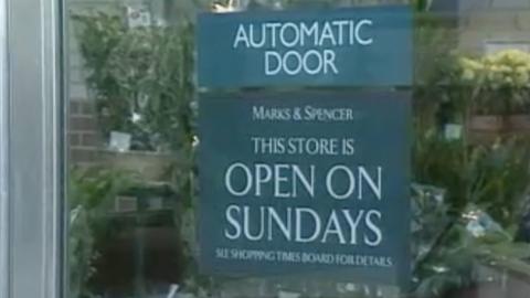 A sign on the door of an M&S saying it is open on Sundays.