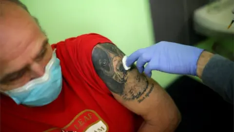 Reuters A man sits after receiving a dose of AstraZeneca's coronavirus disease (COVID-19) vaccine administered by a medical personnel from a mobile unit in the village of Ogden, Bulgaria, 25 February 2021.