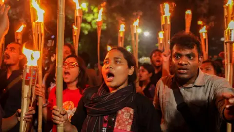 Getty Images Protesters holding flaming lanterns shout in unison