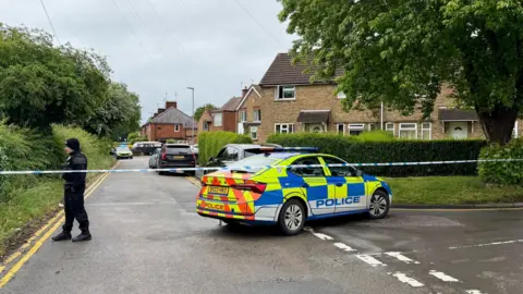 Leicester Media Online A police officer and a police car behind a cordon on a residential street