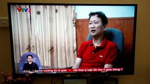 Reuters Thanh is seen seated in a chair in a TV news report. The photo is of a TV showing the broadcast.