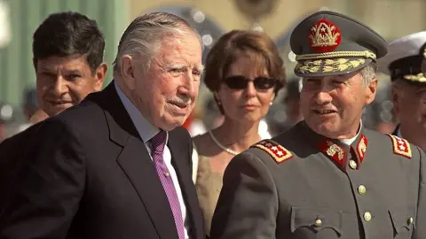 Getty Images Augusto Pinochet (izquierda) camina con el general del ejército Ricardo Izurieta a su llegada a Santiago, Chile, el 3 de marzo de 2000. Pinochet abandonó Gran Bretaña el 2 de marzo después de que el secretario del Interior británico, Jack Straw, anunciara su decisión de liberarlo por motivos de salud.