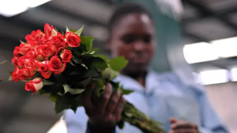 Getty Images A Kenyan flower worker holding a bunch of roses