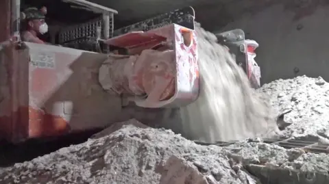 PA Media A man at work in Boulby Mine. The man is operating machinery which is cutting the salt in the mine. 